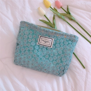 Detail of light blue lace makeup bag with floral embroidery and Time To Party label