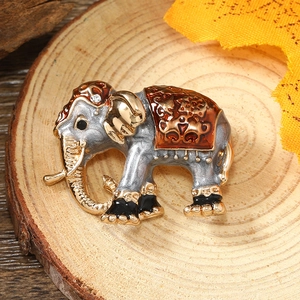 Macro shot of silver-gray elephant brooch with gold trim on circular wooden slice