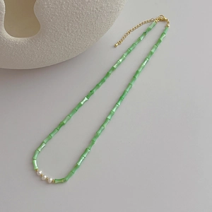 Macro detail of light green bamboo beads and white pearls on a gold-plated link chain