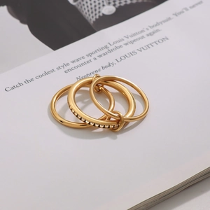 Detailed view of triple-linked gold rings with shimmering zircon inlay on a fashion magazine