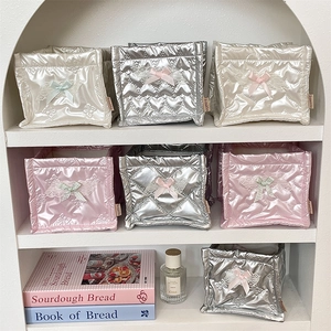Close-up of quilted bow storage bags in pink and silver on a decorative arched shelf