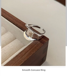 Macro shot of polished S925 sterling silver concave saddle ring on a wooden jewelry box