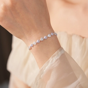 Close-up of a silver heart bracelet with purple enamel and white zircon crystals