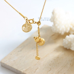Golden Chinese gourd necklace with Fu character charm on white marble background