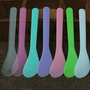 Set of seven colorful 13cm plastic spatula tools for facial mask mixing on rustic background