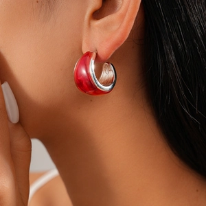 Close-up of red resin and silver geometric C-shaped earring on a model's ear
