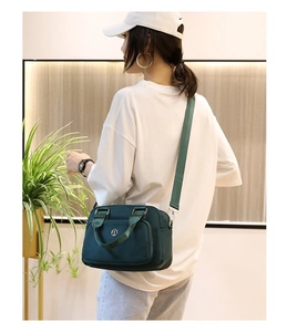 Fashionable dark green nylon crossbody bag with top handle and adjustable strap detail