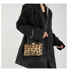 Fashionable leopard print evening clutch bag with gold chain strap shown on a black blazer