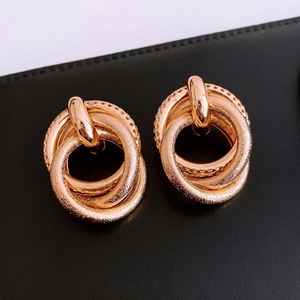 Macro detail of rose gold interlaced knot earrings with polished and frosted textures