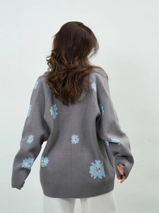 Detail of grey knitted cardigan with blue daisy embroidery on the back in a loose fit