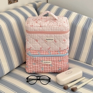 Detail of quilted floral makeup bags with bow patterns and durable carrying handles
