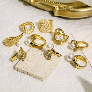 Detailed close-up of luxury gold rings with pearls and sparkling rhinestones on textured stone