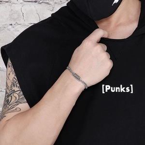 Dettaglio del bracciale punk industriale con molla e catena cubana su polso maschile