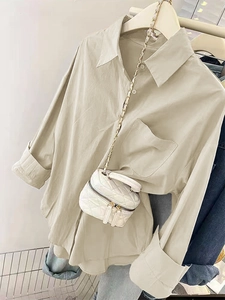Détail de chemise beige à boutons avec poche poitrine et sac matelassé blanc à chaîne