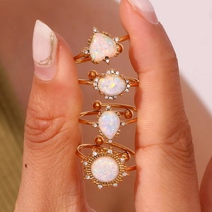 Detail of 18K gold plated rings set with white opal heart and teardrop shapes