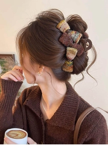 Détail de la pince à cheveux nœud en tweed avec texture tissée et fini brun mat