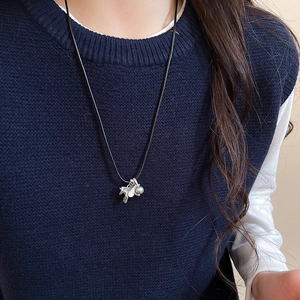 Gros plan d'un pendentif cheval en argent avec perle sur un cordon noir minimaliste