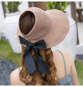 Detail of a brown woven sun visor featuring a large black satin bow for summer protection