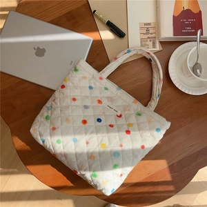 Top-down view of a quilted polka dot tote bag on a wooden table with lifestyle props