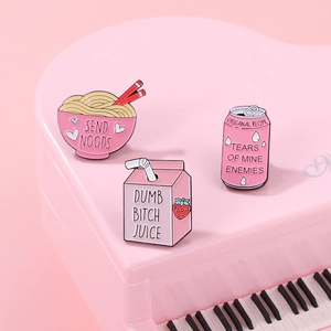 Detailed close-up of pink enamel pins featuring funny food designs on a toy piano