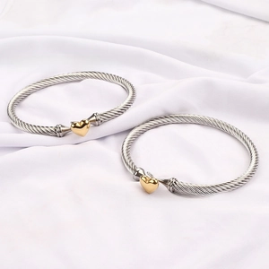 Detail of silver twisted cable cuff bracelet featuring a golden heart center clasp