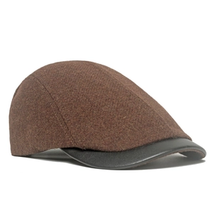Detailed side view of vintage wool flat cap with brown fabric and black leather brim