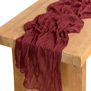 Primer plano del camino de mesa de gasa rojo oscuro con textura arrugada sobre madera