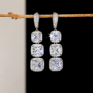 Detailed view of silver dangle earrings with three square crystals on a natural twig