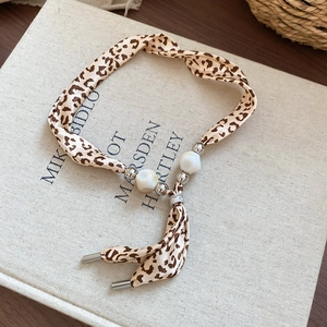 Vue détaillée du collier ruban léopard avec des perles irrégulières et des embouts en métal