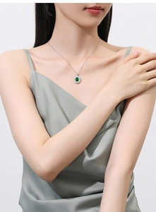 Detailed view of an oval emerald pendant on a S925 silver chain worn by a female model