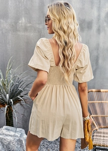 Detail view of beige romper showing elastic smocked back and puffed sleeves from behind