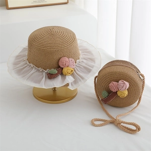 Detail of straw hat and round bag set with floral decor and white wavy tulle trim