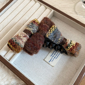 Detailed close-up of a flocking bow hair claw clip with tweed knit fabric on a jewelry box