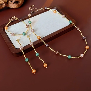 Detailed set of wavy gold necklaces, bracelets, and earrings with colorful pearls