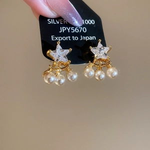 Detail of star-shaped zircon and pearl drop earrings in gold-plated Silver 1000