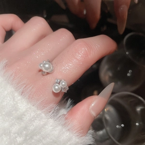 Close-up of adjustable silver ring with zircon accents and multiple pearls on a finger
