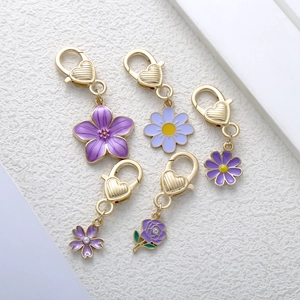 Set of 5 golden floral keychains with purple enamel flowers and sparkling rhinestones