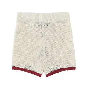 Detailed view of beige knitted shorts featuring red wavy crochet trim and textured fabric