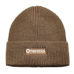 Detail of rib-knit brown beanie with rectangular woven patch showing THE FOCUS logo