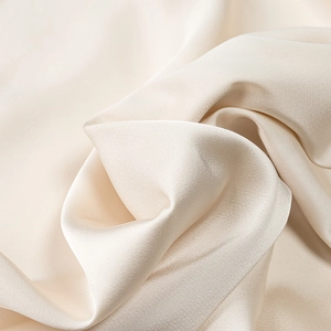 Dettaglio dell'elegante tessuto di raso beige con morbida seta e riflessi lucidi naturali