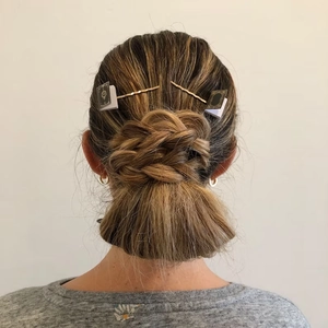 Detail shot of mini book-shaped hair clips styled on a braided bun for book lovers