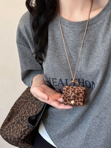 Detailed close-up of leopard print faux fur mini bag pendant with golden metal snap button