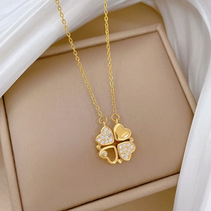 Macro detail of gold four-leaf clover pendant with crystal heart petals on an O-chain
