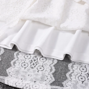 Détail de la broderie en dentelle blanche sur la doublure lisse de cette robe chic