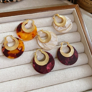 Three pairs of acetate round pendant earrings with gold textured hoops in various marble patterns