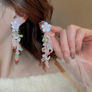 Detail of colorful smiley face beaded tassel earrings with iridescent white flower