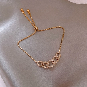 Detailed view of gold slider bracelet featuring four oval crystal charms and a silk background