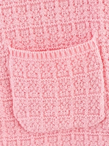 Detail of pink knitted dress set showing thick pocket stitching and soft fabric texture