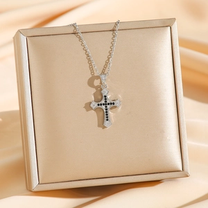 Chic silver cross necklace with black and white pavé cubic zirconia on satin background