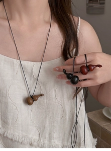 Détails de pendentifs gourde en bois naturel avec textures boisées et cordon noir fin